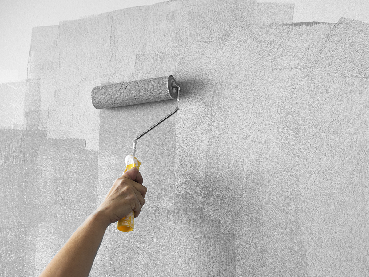 Woman repainting her wall a neutral gray